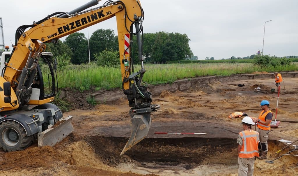 Een graafmachine graaft een oude waterput uit.